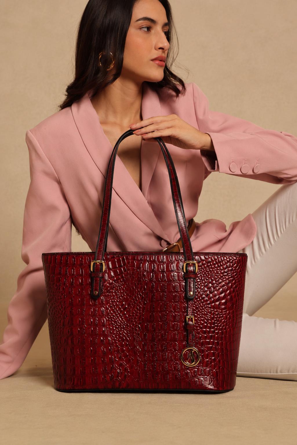 Woman holding a red textured MASHAK tote handbag against a beige background