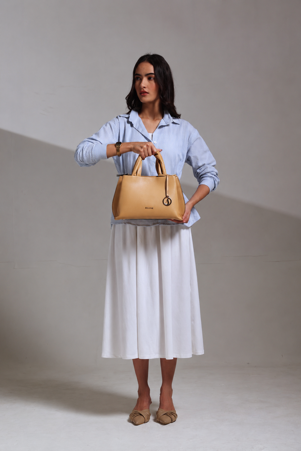 Woman holding a BEIGE MASHAK handbag against a plain background